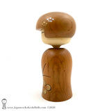 A side view photo (left side) of an original, one-of-a-kind modern kokeshi doll by Isao Sasaki. Handmade from beautifully grained hardwood. A pretty kokeshi with a calm expression.