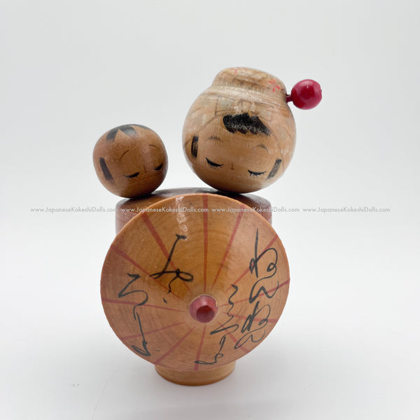 This kokeshi doll pair depicts a Japanese mother with a baby on her back. The mom is very elegant: she has lovely long lashes a cute pink hairpin and she's carrying a traditional Japanese umbrella that she can use to protect her baby from the sun or rain.  This vintage handmade wooden doll was made circa 1960s or early 70s.