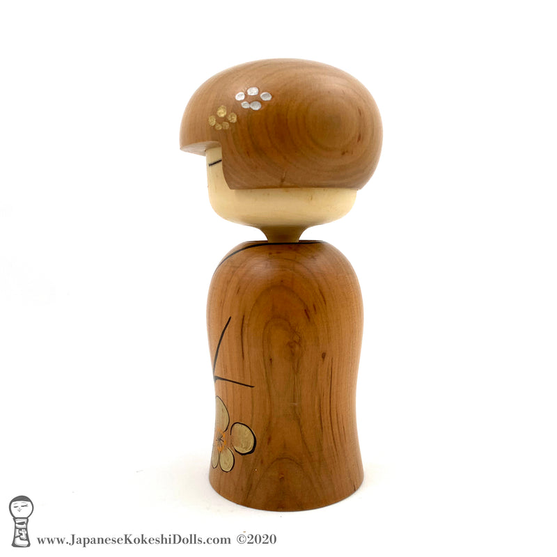 A side view photo (left side) of an original, one-of-a-kind modern kokeshi doll by Isao Sasaki. Handmade from beautifully grained hardwood. A pretty kokeshi with a calm expression.